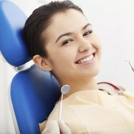 Woman looking at digital xrays and smiling in a dental chair