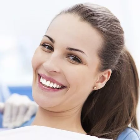 Woman looking at digital xrays and smiling in a dental chair
